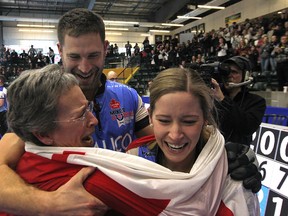 John Morris and Kaitlyn Lawes are wrapped in a Canada flag with Lawes' mother Cheryl after winning the mixed doubles Olympic trials final over Brad Gushue and Val Sweeting in Portage la Prairie, Man., on Sunday.