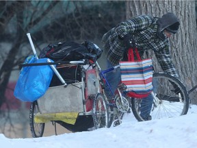 Not very well dressed for the -26C dawn weather, a man manoeuvres a bicycle and trailer along a path that leads underneath a bridge, in Winnipeg, where homeless people are known to camp.