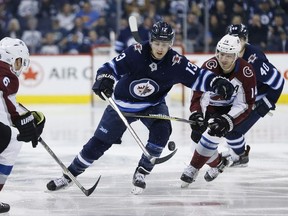 Winnipeg Jets' Brandon Tanev (13) and Colorado Avalanche's Blake Comeau (14) chase down a loose puck during second period NHL action in Winnipeg on Saturday, February 3, 2018.