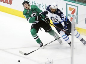 Jets defenceman Dustin Byfuglien (33) and Stars forward Mattias Janmark (13) battle for the puck during the second period in Dallas last night. AP Photo/Brandon Wade.