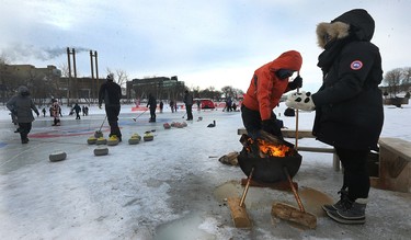 People warm up by the fire during the 17th annual Ironman Outdoor Curling Bonspiel on the Red River at The Forks in Winnipeg on Sun., Feb. 4, 2018. Kevin King/Winnipeg Sun/Postmedia Network