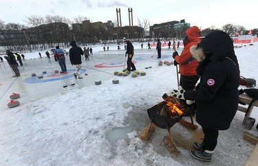 People warm up by the fire during the 17th annual Ironman Outdoor Curling Bonspiel on the Red River at The Forks in Winnipeg on Sun., Feb. 4, 2018. Kevin King/Winnipeg Sun/Postmedia Network