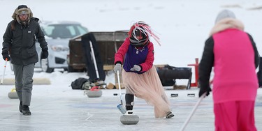 A competitor pushes her shot with a broom during the 17th annual Ironman Outdoor Curling Bonspiel on the Red River at The Forks in Winnipeg on Sun., Feb. 4, 2018. Kevin King/Winnipeg Sun/Postmedia Network