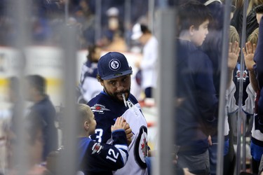 Dustin Byfuglien has an assistant as he signs autographs from the bench during the Winnipeg Jets skills competition at Bell MTS Place in Winnipeg on Wed., Feb. 14, 2018. Kevin King/Winnipeg Sun/Postmedia Network