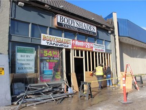 Workers put up a makeshift wooden wall after a car crashed through the front of Body Shades Tanning Salon & Spa on Sunday morning.