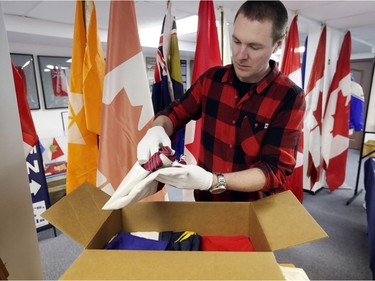 Shayne Campbell, who is the president and executive director of Settlers, Rails & Trails, unpacks flags from the Ralph Spence collection which arrived at the local museum in Argyle, Man., located 50 kilometres northwest of Winnipeg, Man. on Friday, March 2, 2018. (Brook Jones/Stonewall Argus & Teulon Times/Postmedia Network)