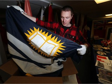 Shayne Campbell, who is the president and executive director of Settlers, Rails & Trails, looks at a flag from the Ralph Spence collection which arrived at the local museum in Argyle, Man., located 50 kilometres northwest of Winnipeg, Man. on Friday, March 2, 2018. (Brook Jones/Stonewall Argus & Teulon Times/Postmedia Network)