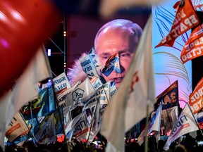 People listen to presidential candidate, President Vladimir Putin during a rally and a concert celebrating the fourth anniversary of Russia's annexation of Crimea at Manezhnaya Square in Moscow on March 18, 2018.