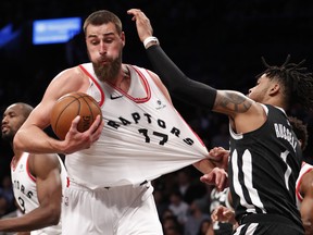 Brooklyn Nets guard D'Angelo Russell, right, grabs the jersey of Toronto Raptors center Jonas Valanciunas (17), for which he drew a foul call, Tuesday, March 13, 2018, in New York. The Raptors defeated the Nets 116-102. The Associated Press