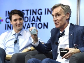 Bill Nye shows off a Canadian $5 bill, which features an astronaut and the Canadarm as Prime Minister Justin Trudeau looks on during an armchair discussion highlighting Budget 2018's investments in Canadian innovation at the University of Ottawa in Ottawa on Tuesday, March 6, 2018.
