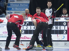 Ontario skip John Epping, right, watches as Team Canada third Mark Nichols, skip Brad Gushue and lead Geoff Walker, left to right, move a rock during play Friday night at the Tim Hortons Brier at the Brandt Centre in Regina on Friday night.