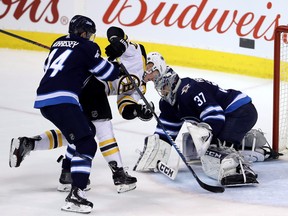 Winnipeg Jets' Josh Morrissey (44) hits Boston Bruins' Ryan Donato (17) into Jets goaltender Connor Hellebuyck (37) during first period NHL hockey action in Winnipeg, Tuesday, March 27, 2018. THE CANADIAN PRESS/Trevor Hagan ORG XMIT: WPGT106