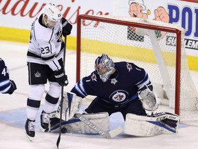 Winnipeg Jets goaltender Eric Comrie (1) stops a shot with Los Angeles Kings right wing Dustin Brown (23) standing in front during second period NHL hockey action in Winnipeg, Tuesday, March 20, 2018. THE CANADIAN PRESS/Trevor Hagan