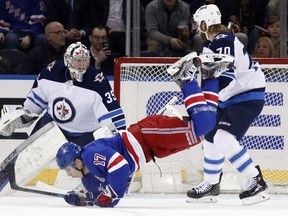 Rangers winger Jesper Fast trips in front of Winnipeg Jets goaltender Steve Mason and defenceman Joe Morrow during the first period in New York on Monday night. (The Associated Press)
