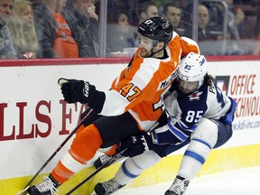 Philadelphia Flyers' Andrew MacDonald, left, and Winnipeg Jets' Mathieu Perrault vie for the puck during the first period Saturday in Philadelphia.