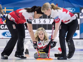 Canada lead Dawn McEwen, right, and second Jill Officer sweep a rock delivered by skip Jennifer Jones as they play Sweden in the gold medal game at the World Women's Curling Championship Sunday, March 25, 2018 in North Bay, Ont. THE CANADIAN PRESS/Paul Chiasson