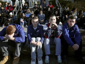 In this Feb. 28, 2018, file photo, Somerville High School students sit on the sidewalk on Highland Avenue during a student walkout at the school in Somerville, Mass. Walkouts were staged in the U.S. and Canada last week.