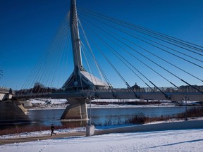 A woman runs on a path along the Assiniboine River as the Provencher pedestrian bridge towers above her in Winnipeg, Man., on Monday November 30, 2015. Manitoba's latest flood forecast predicts the province is at a relatively low risk for major spring flooding.
