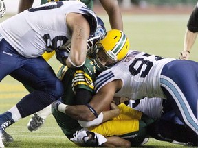 Argonauts' Cleyon Laing (90) and Ivan Brown (97) hit Eskimos quarterback Mike Reilly (13) during CFL action in Edmonton on Sept. 28, 2013. Reilly sustained a helmet-to-helmet hit on this play and was diagnosed with a concussion.