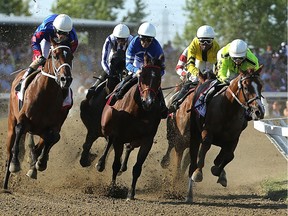 Horses enter the first turn during the Manitoba Derby at Assiniboia Downs in Winnipeg on Monday, Aug. 7, 2017.