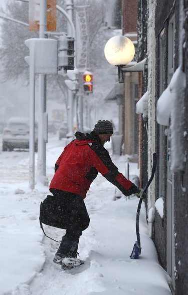 A shop owner brings a bag and shovel to work on Corydon Avenue in Winnipeg on Mon., March 5, 2018. Kevin King/Winnipeg Sun/Postmedia Network