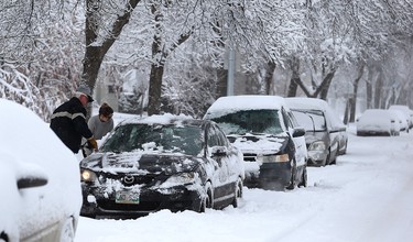 Residents clear a car of snow on Warsaw Avenue in Winnipeg on Mon., March 5, 2018. Kevin King/Winnipeg Sun/Postmedia Network