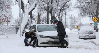 Hans Baptista (left) helps Barry Giesbrecht with his stuck vehicle on Nassau Street North in Winnipeg on Mon., March 5, 2018. Kevin King/Winnipeg Sun/Postmedia Network
