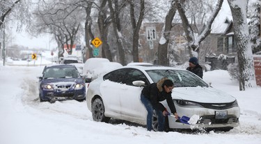 Hans Baptista (left) helps Barry Giesbrecht with his stuck vehicle on Nassau Street North in Winnipeg on Mon., March 5, 2018. Kevin King/Winnipeg Sun/Postmedia Network