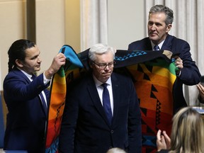 Former Premier Greg Selinger (centre) is wrapped in a ceremonial blanket by NDP Leader Wab Kinew (left) and Premier Brian Pallister during his final day in the Manitoba Legislature in Winnipeg on Wed., March 7, 2018. Kevin King/Winnipeg Sun/Postmedia Network