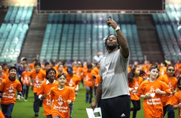 Saskatchewan Roughriders running back Jerome Messam  uses his phone to capture students running a lap during a Jumpstart event at the RBC Convention Centre that is part of CFL Week in Winnipeg on Thurs., March 22, 2018. Over 150 kids from Greenway and Victory schools were able to participate in drills with current CFL stars. Kevin King/Winnipeg Sun/Postmedia Network