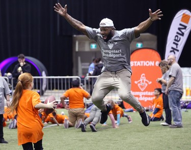 Hamilton Tiger-Cats linebacker Simoni Lawrence celebrates with a student during a Jumpstart event at the RBC Convention Centre that is part of CFL Week in Winnipeg on Thurs., March 22, 2018. Over 150 kids from Greenway and Victory schools were able to participate in drills with current CFL stars. Kevin King/Winnipeg Sun/Postmedia Network