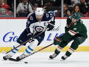 Zach Parise (11) of the Minnesota Wild reaches for the puck against Blake Wheeler (26) of the Winnipeg Jets during the second period in Game 3 Sunday.