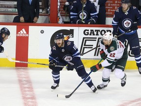 Bryan Little (18) of the Winnipeg Jets and Nino Niederreiter (22) of the Minnesota Wild chase an airborne puck in Game 5 Friday.