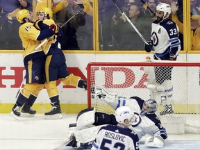 Nashville Predators left wing Kevin Fiala, second from left, of Switzerland, celebrates with Craig Smith (15) as Winnipeg Jets defenseman Dustin Byfuglien (33) skates by after Fiala scored the winning goal against goalie Connor Hellebuyck (37) during the second overtime in Game 2 of an NHL hockey second-round playoff series, Sunday, April 29, 2018, in Nashville, Tenn. The Predators won 5-4 to tie the series 1-1. (AP Photo/Mark Humphrey) ORG XMIT: TNMH129