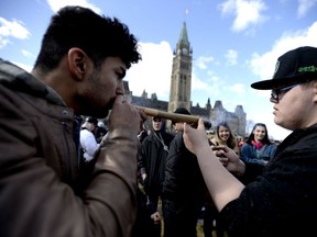 A man shares his marijuana joint during the annual 4/20 marijuana celebration on Parliament Hill in Ottawa on Friday, April 20, 2018.