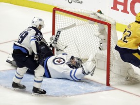Predators winger Kevin Fiala scores the winning goal against Jets goalie Connor Hellebuyck during the second overtime period in Game 2 of their second-round playoff series on Sunday in Nashville. (The Associated Press)