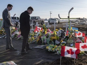 A group of Saskatchewan Junior Hockey League referees look at a memorial at the intersection of a fatal bus crash that killed 16 members of the Humboldt Broncos hockey team last week near Tisdale, Sask. on Saturday, April 14, 2018. (Liam Richards/THE CANADIAN PRESS)