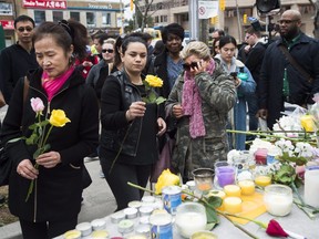 Ozra Kenari, right, cries after placing flowers at a memorial for the victims along Yonge Street the day after a driver drove a rented van down sidewalks Monday afternoon, striking pedestrians in his path, in Toronto, Tuesday, April 24, 2018. THE CANADIAN PRESS/Nathan Denette