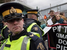 An RCMP officer reads a court order to Federal Green Party Leader Elizabeth May, right, and NDP MP Kennedy Stewart, second right, before they were arrested after joining protesters outside Kinder Morgan's facility in Burnaby, B.C., on Friday March 23, 2018.