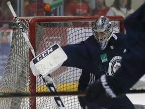 A shot pops the water bottle behind goaltender Connor Hellebuyck during Winnipeg Jets practice at Bell MTS Iceplex on Monday.