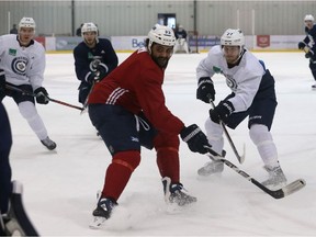 Dustin Byfuglien (centre) battles for the puck with Nikolaj Ehlers (right) during Winnipeg Jets practice at Bell MTS Iceplex.