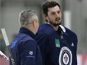 Connor Hellebuyck (right) speaks with goaltending coach Wade Flaherty during Winnipeg Jets practice at Bell MTS Iceplex on Tuesday.