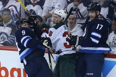 Andrew Copp (left) and Adam Lowry (right) of the Winnipeg Jets hit Minnesota Wild defenceman Nick Seeler during Game 1 of their first-round NHL playoff series in Winnipeg on Wed., April 11, 2018. Kevin King/Winnipeg Sun/Postmedia Network