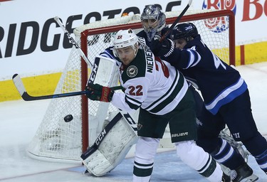 Minnesota Wild forward Nino Niederreiter (left) tips a shot as he's checked by Winnipeg Jets defenceman Josh Morrissey in front of goaltender Connor Hellebuyck during Game 1 of their first-round NHL playoff series in Winnipeg on Wed., April 11, 2018. Kevin King/Winnipeg Sun/Postmedia Network