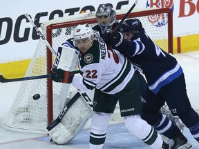 Minnesota Wild forward Nino Niederreiter (left) tips a shot as he's checked by Winnipeg Jets defenceman Josh Morrissey in front of goaltender Connor Hellebuyck during Game 1 of their first-round NHL playoff series in Winnipeg on Wed., April 11, 2018. Kevin King/Winnipeg Sun/Postmedia Network