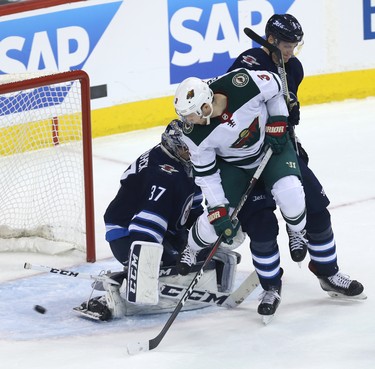 Minnesota Wild centre Charlie Coyle jumps as he's checked by Winnipeg Jets defenceman Tyler Myers as a shot goes wide on Connor Hellebuyck during Game 1 of their first-round NHL playoff series in Winnipeg on Wed., April 11, 2018. Kevin King/Winnipeg Sun/Postmedia Network