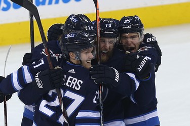 Winnipeg Jets defenceman Joe Morrow (second from right) is mobbed by Nikolaj Ehlers, Patrik Laine and Paul Stastny (from left) after his winning goal against the Minnesota Wild during Game 1 of their first-round NHL playoff series in Winnipeg on Wed., April 11, 2018. Kevin King/Winnipeg Sun/Postmedia Network