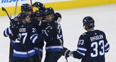 Winnipeg Jets defenceman Joe Morrow (second from right) is mobbed by Nikolaj Ehlers, Patrik Laine and Paul Stastny (from left) as Dustin Byfuglien approaches after his winning goal against the Minnesota Wild during Game 1 of their first-round NHL playoff series in Winnipeg on Wed., April 11, 2018. Kevin King/Winnipeg Sun/Postmedia Network