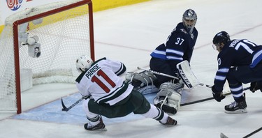 Minnesota Wild forward Zach Parise (left) touches the puck past Winnipeg Jets goaltender Connor Hellebucyk during Game 1 of their first-round NHL playoff series in Winnipeg on Wed., April 11, 2018. Kevin King/Winnipeg Sun/Postmedia Network