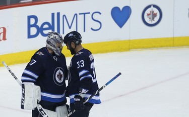 Winnipeg Jets goaltender Connor Hellebuyck (left) and defenceman Dustin Byfuglien close their eyes for a celebratory head bump after beating the Minnesota Wild during Game 1 of their first-round NHL playoff series in Winnipeg on Wed., April 11, 2018. Kevin King/Winnipeg Sun/Postmedia Network